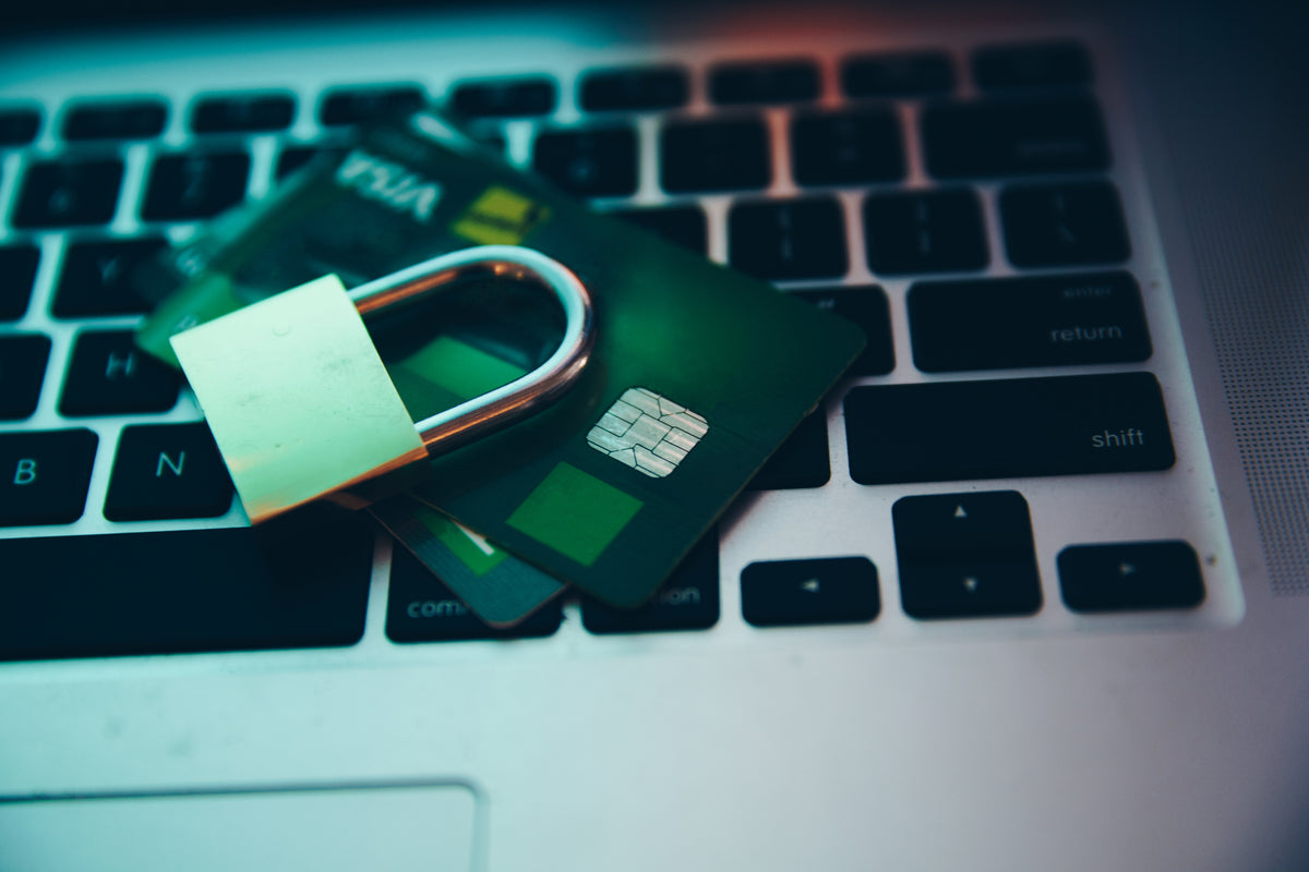 Padlock resting on a Visa credit card atop a laptop keyboard
