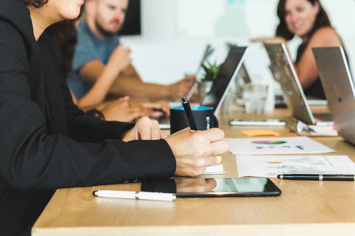 Team meeting at a conference table with laptops, charts and tablet