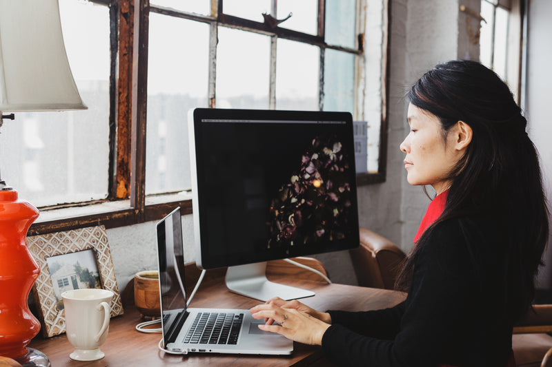 Woman working on a laptop and monitor