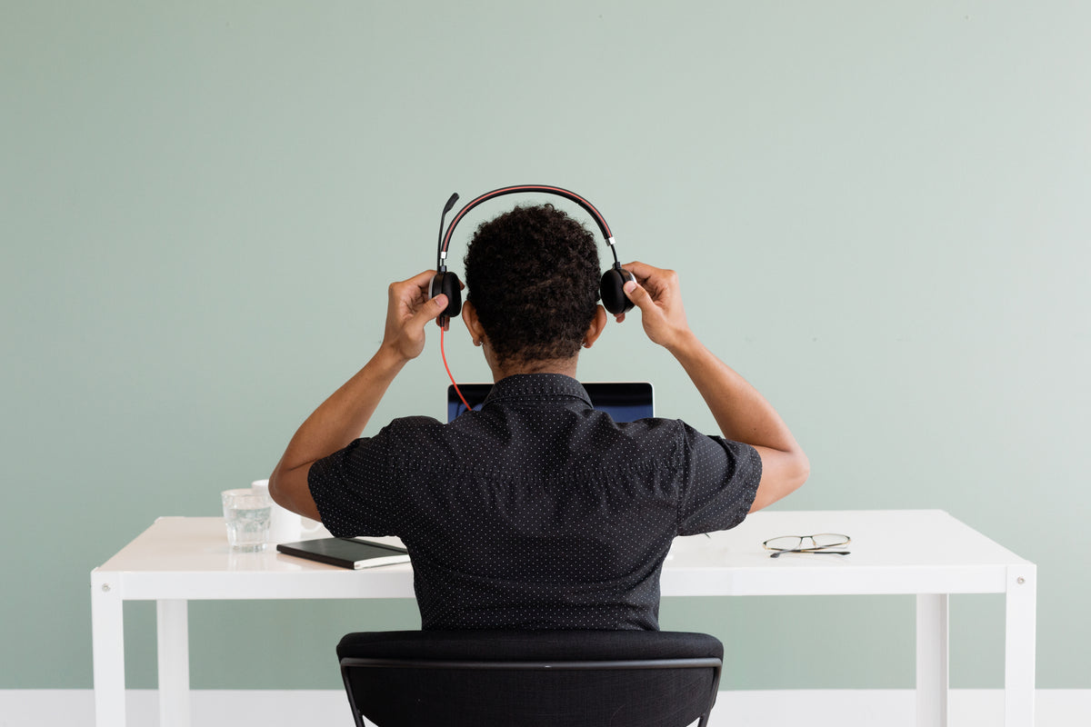 Person at a desk putting on a headset in front of a laptop